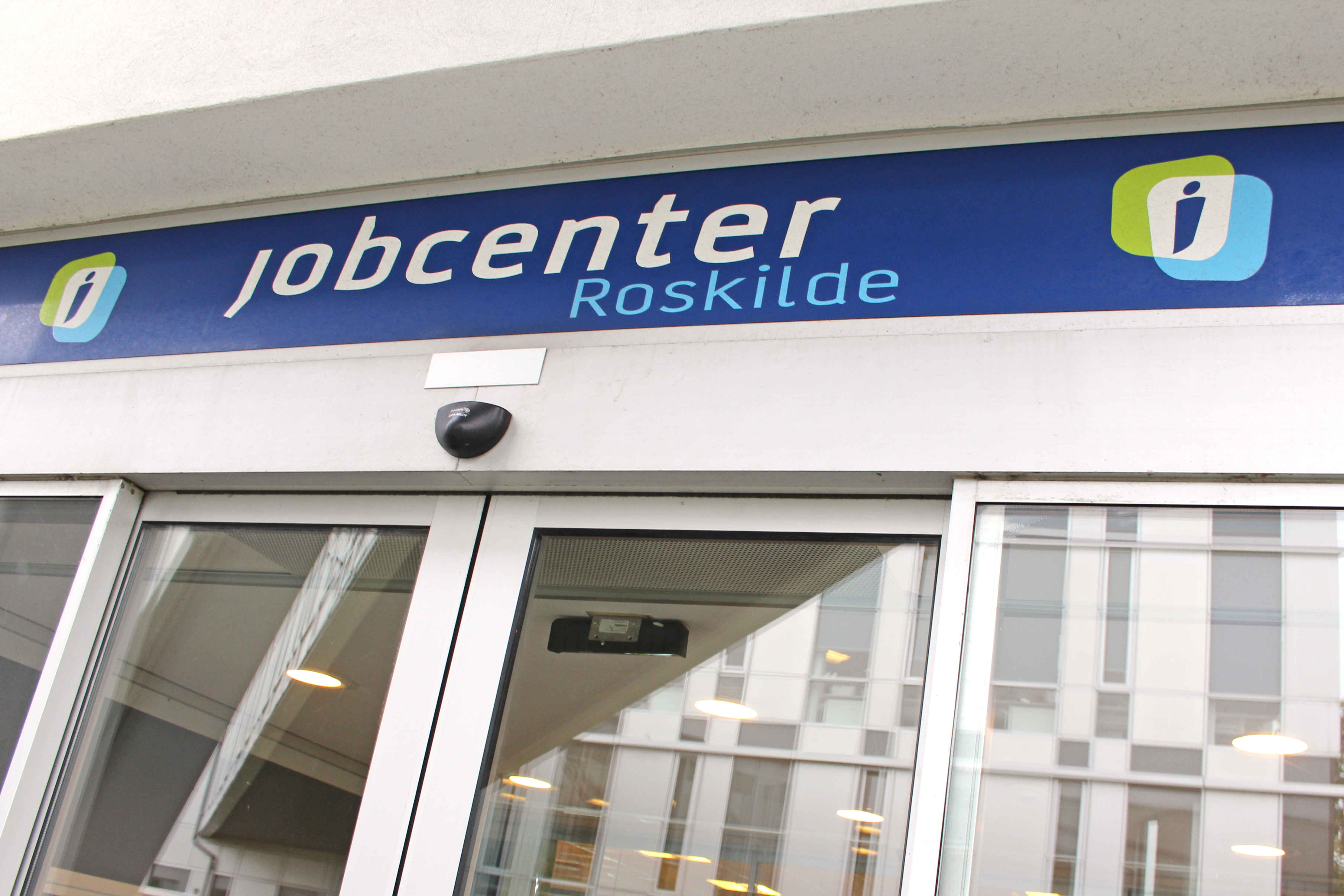 Jobcenter Roskildes indgangsparti med automatiske døre og et blåt skilt.