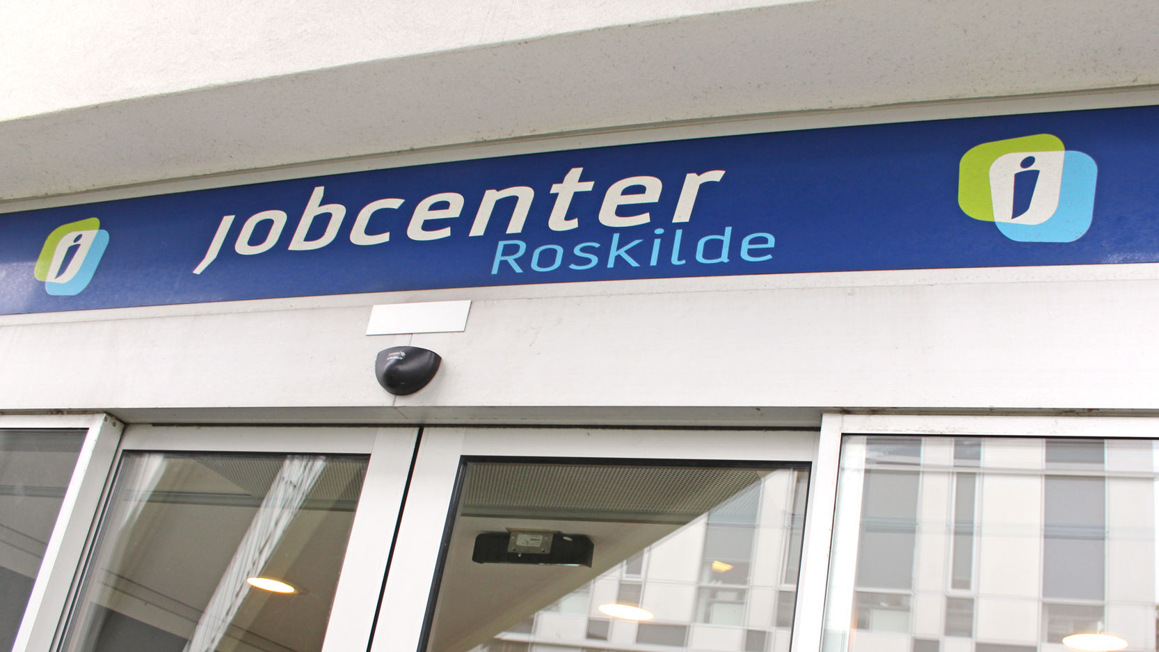Jobcenter Roskildes indgangsparti med automatiske døre og et blåt skilt.