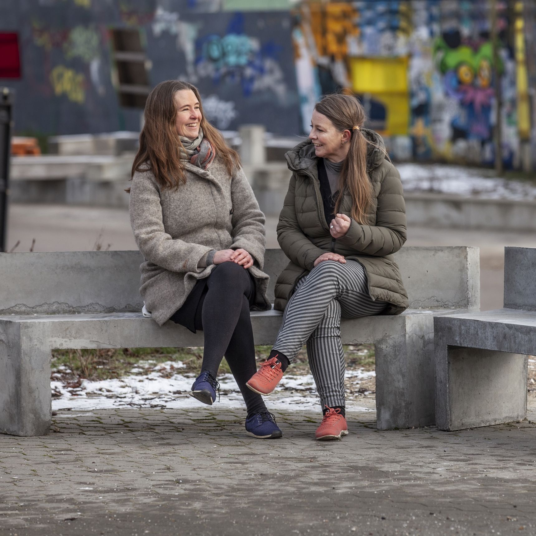To kvinder sidder på betonbænk