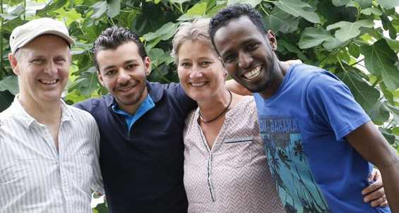 Fire mennesker smiler til kameraet. De har forskellige etniciteter.