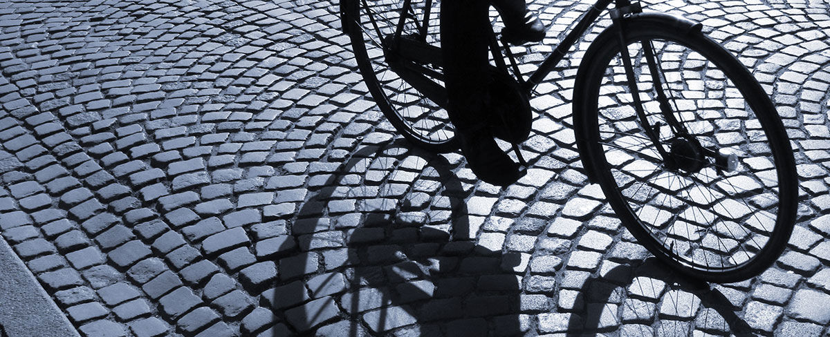 Nederste del af en cykel, der cykler på brosten.